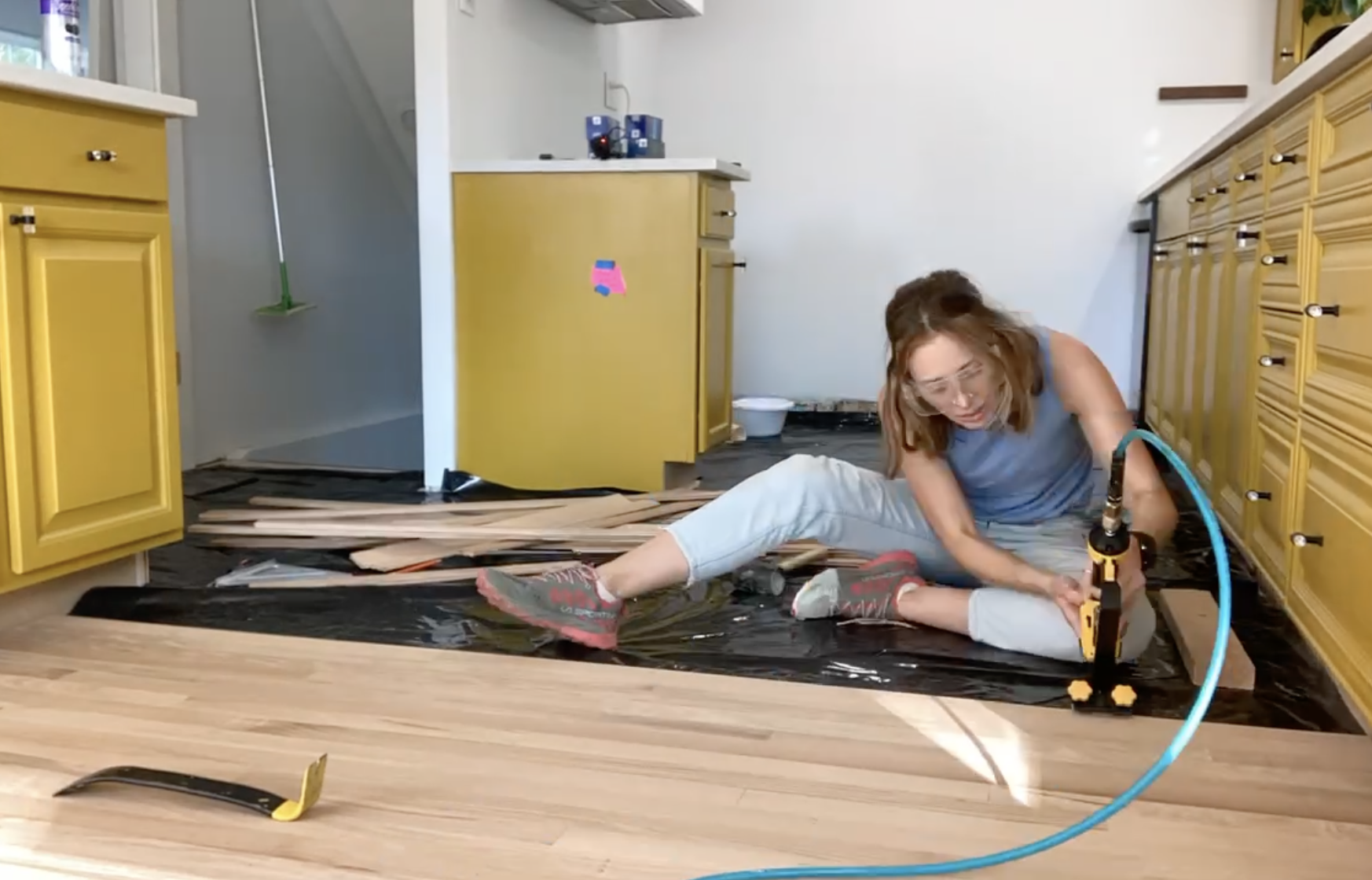 Kelsey instaling hardwood floors in a yellow kitchen