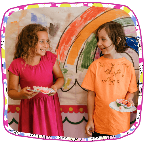 two little girls smiling at each other while standing in front of a mural they made on the wall