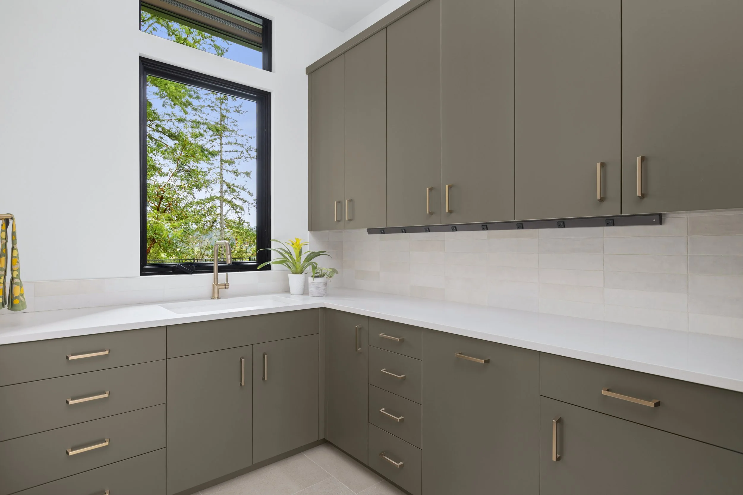 Laundry room sink and cabinetry detail with window view of surrounding trees