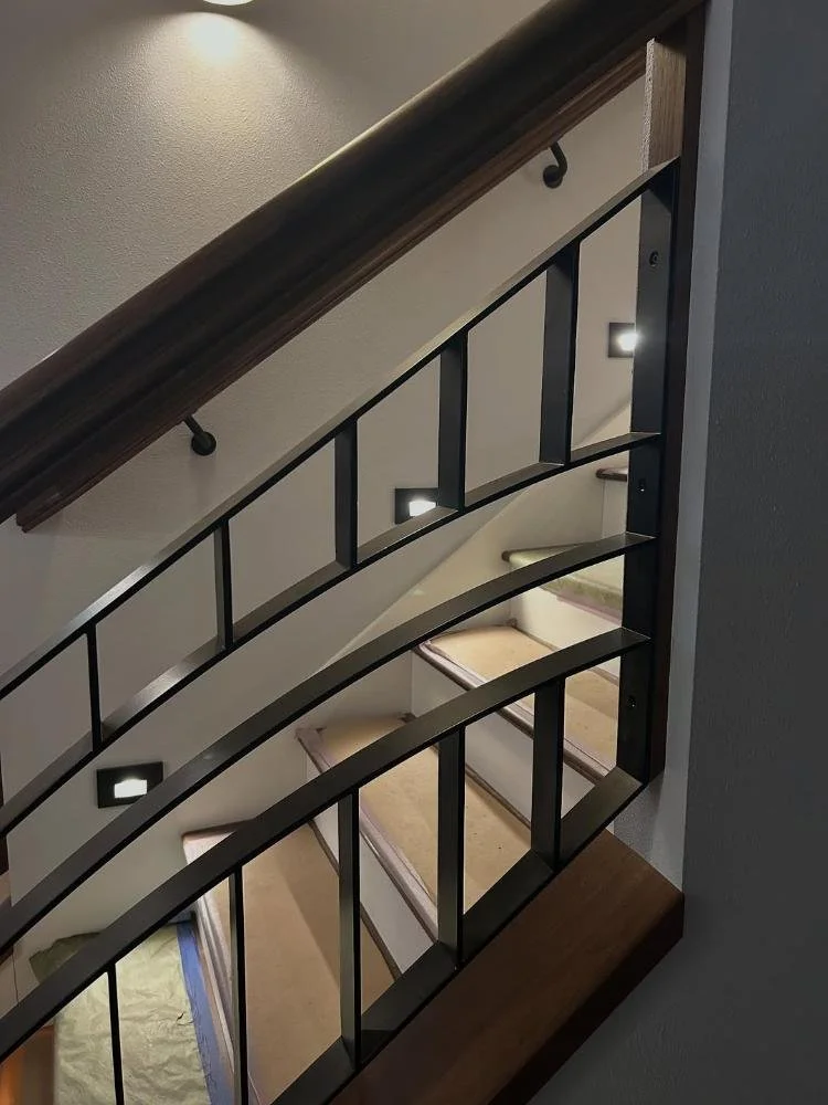 Curved steel flat-bar stair railing with hardwood handrail