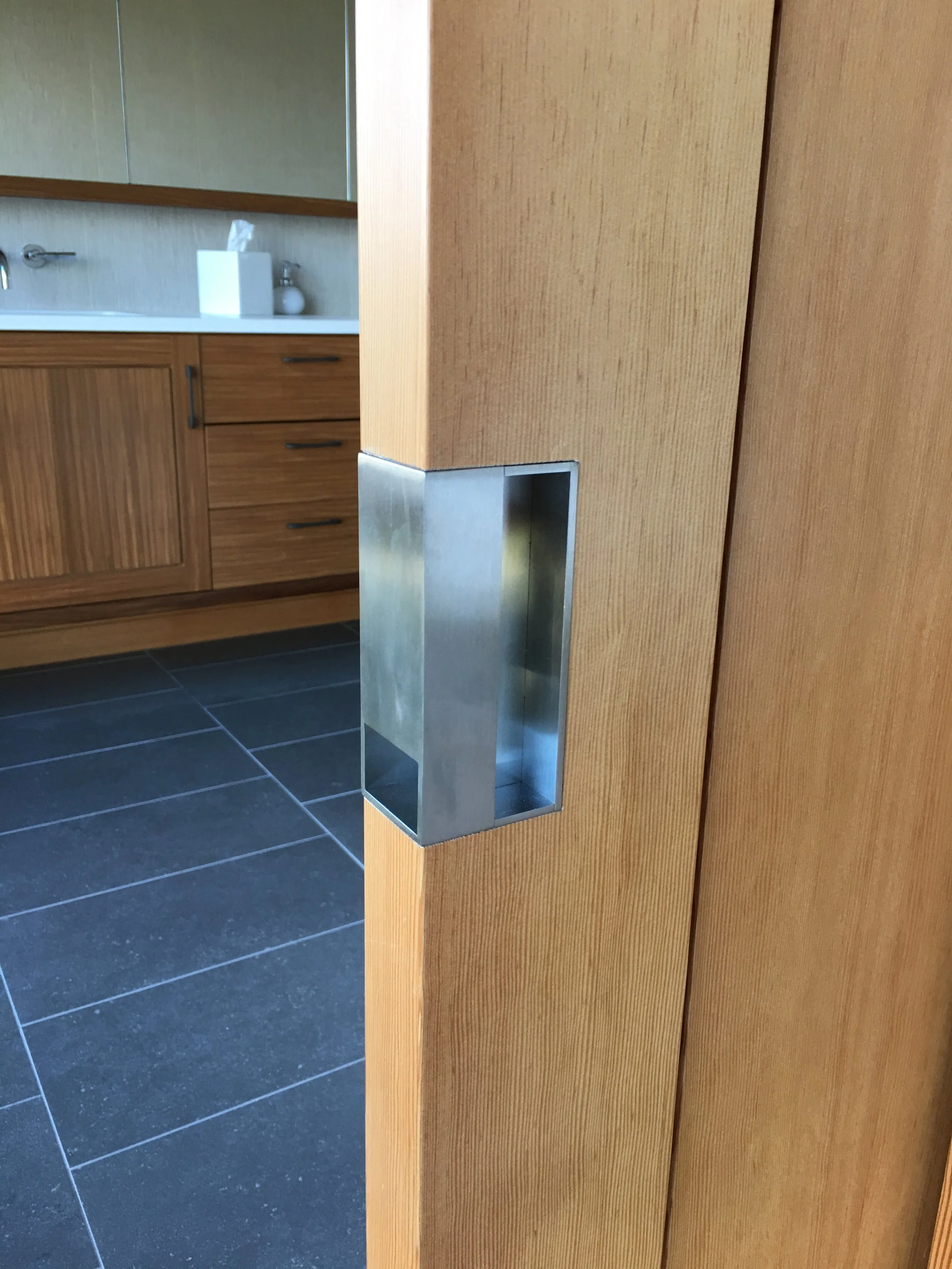 Stainless steel recessed pull set into a wood door