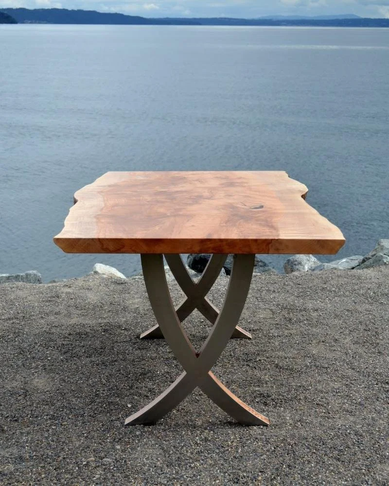 Live-edge slab table on crossed steel arc base