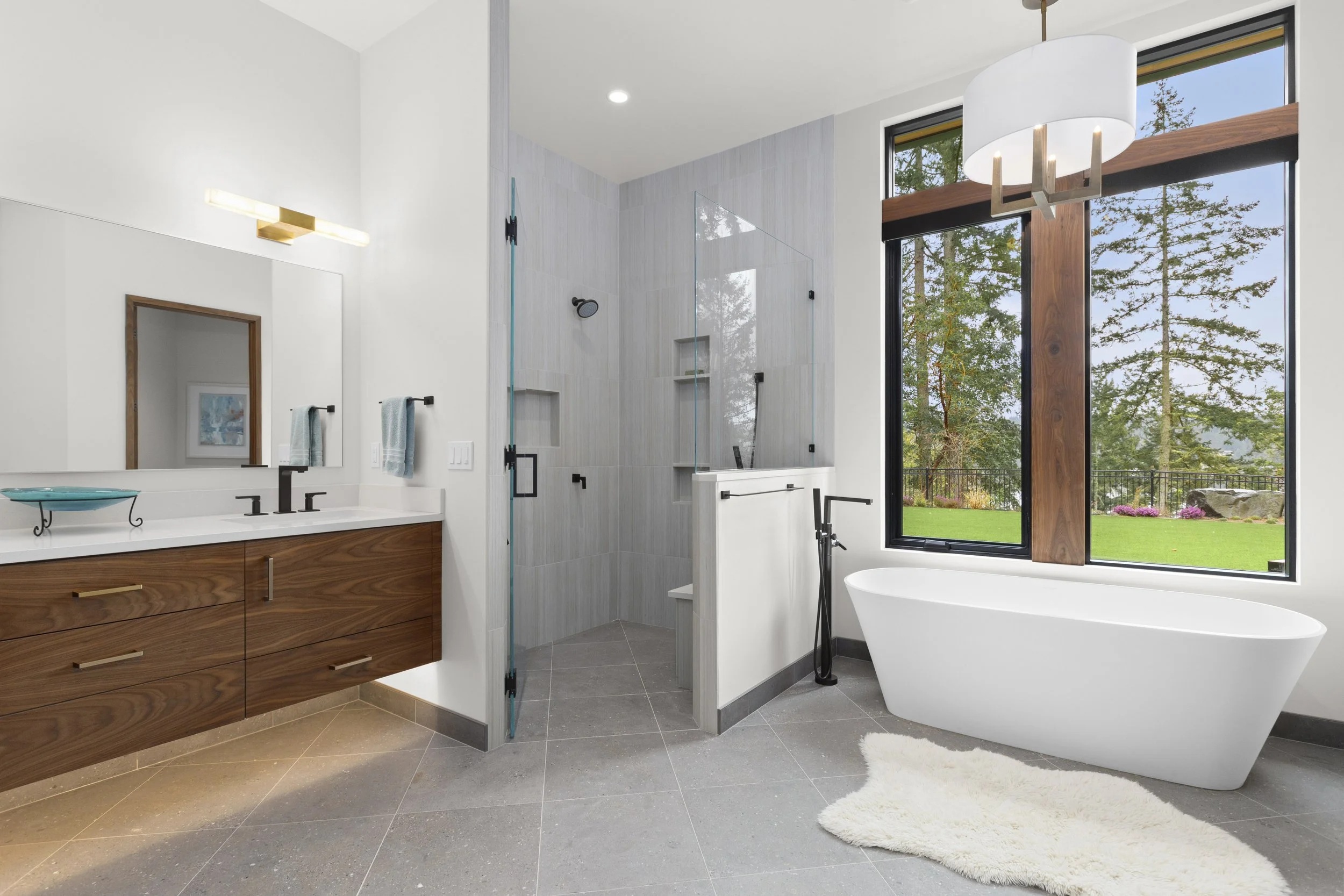Primary bathroom with floating walnut double vanity, illuminated mirrors, and tiled feature wall