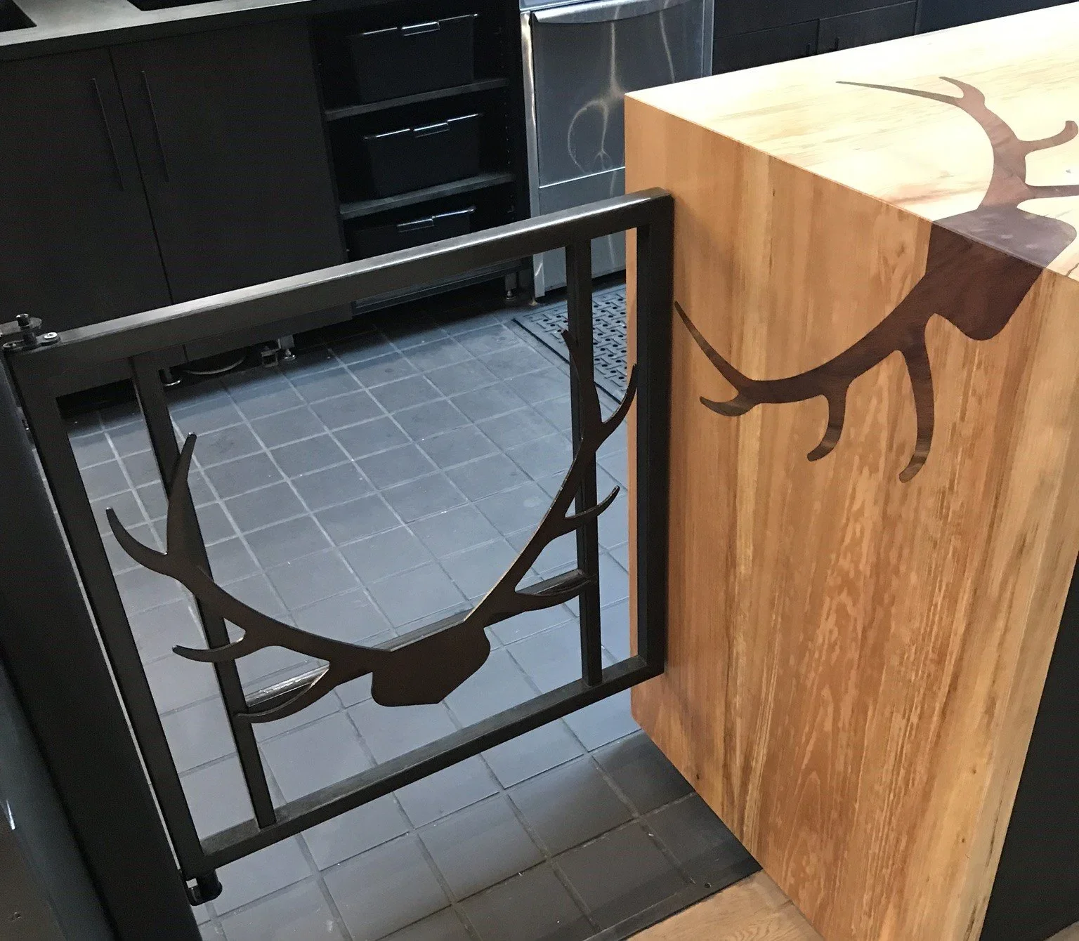 Steel gate with elk antler cutout beside hardwood bar with inlaid antlers, Madera Furniture Tacoma