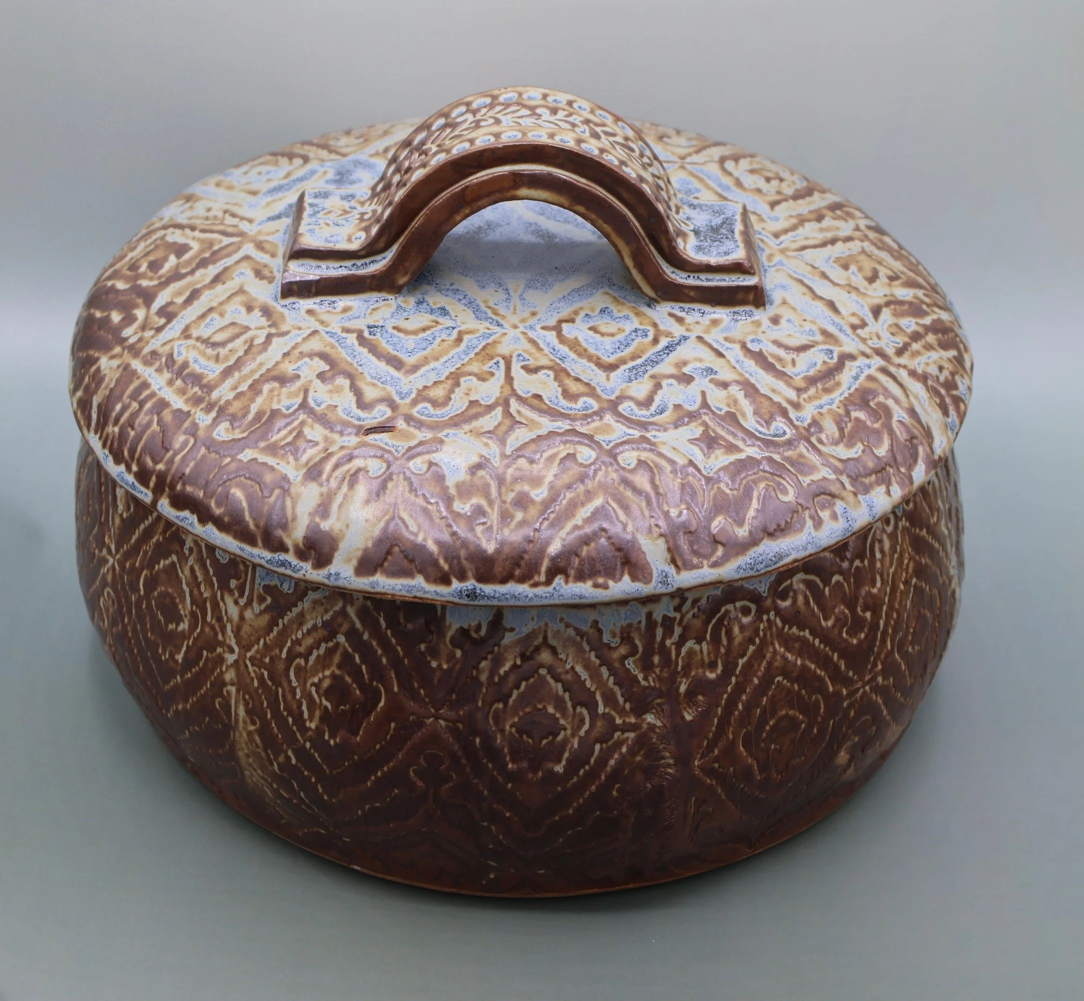 Decorative ceramic container with a lid, featuring intricate geometric patterns in shades of brown, beige, and white.