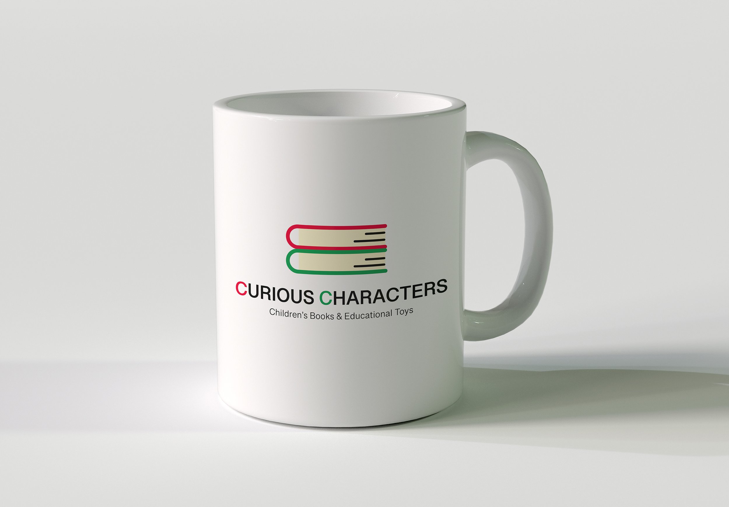 White mug with a logo of an open book in red and green, labeled 'Curious Characters' for children's books and educational toys.