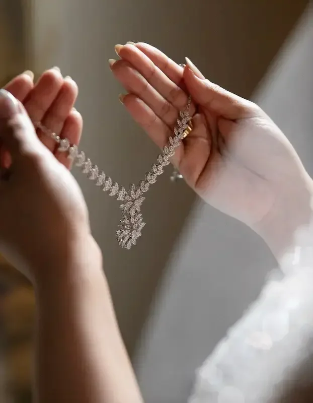 Closeup of hands holding a diamond necklace with a pendant.
