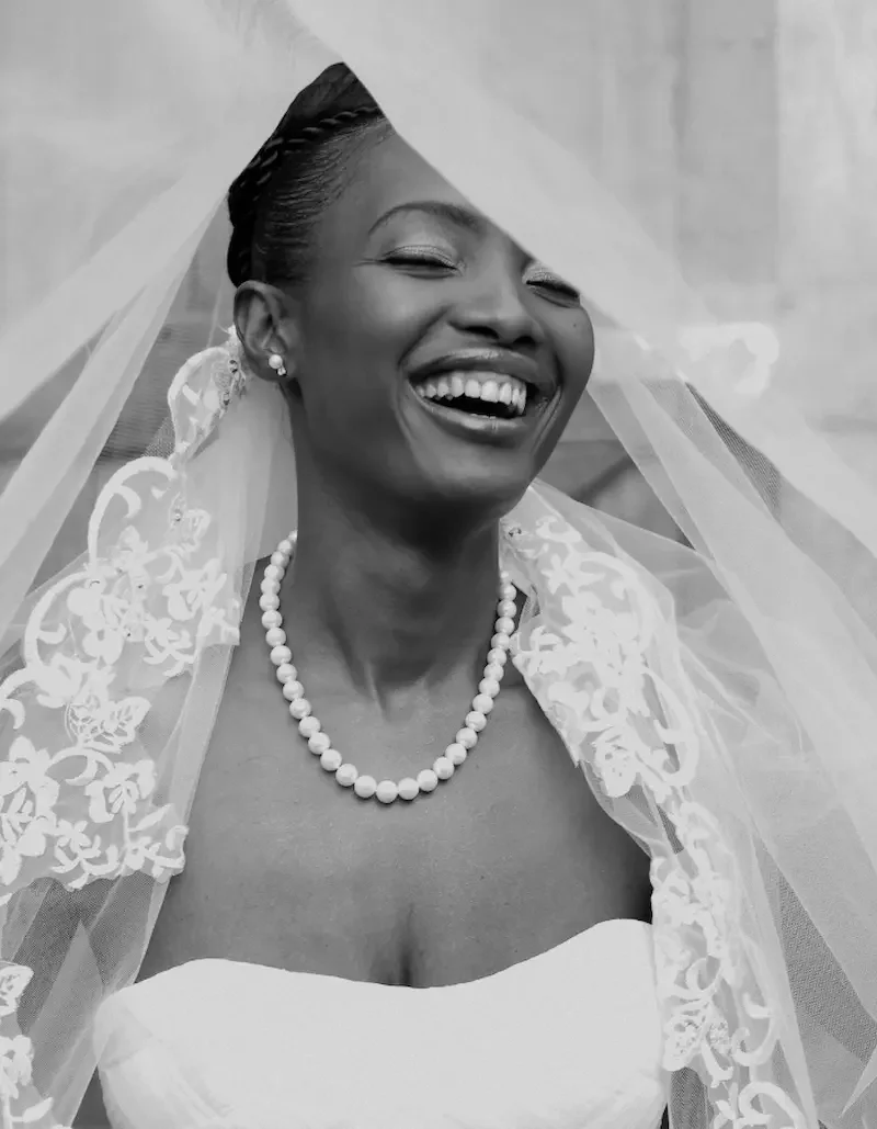 Smiling bride in a wedding dress, wearing a veil, pearl necklace, and earrings