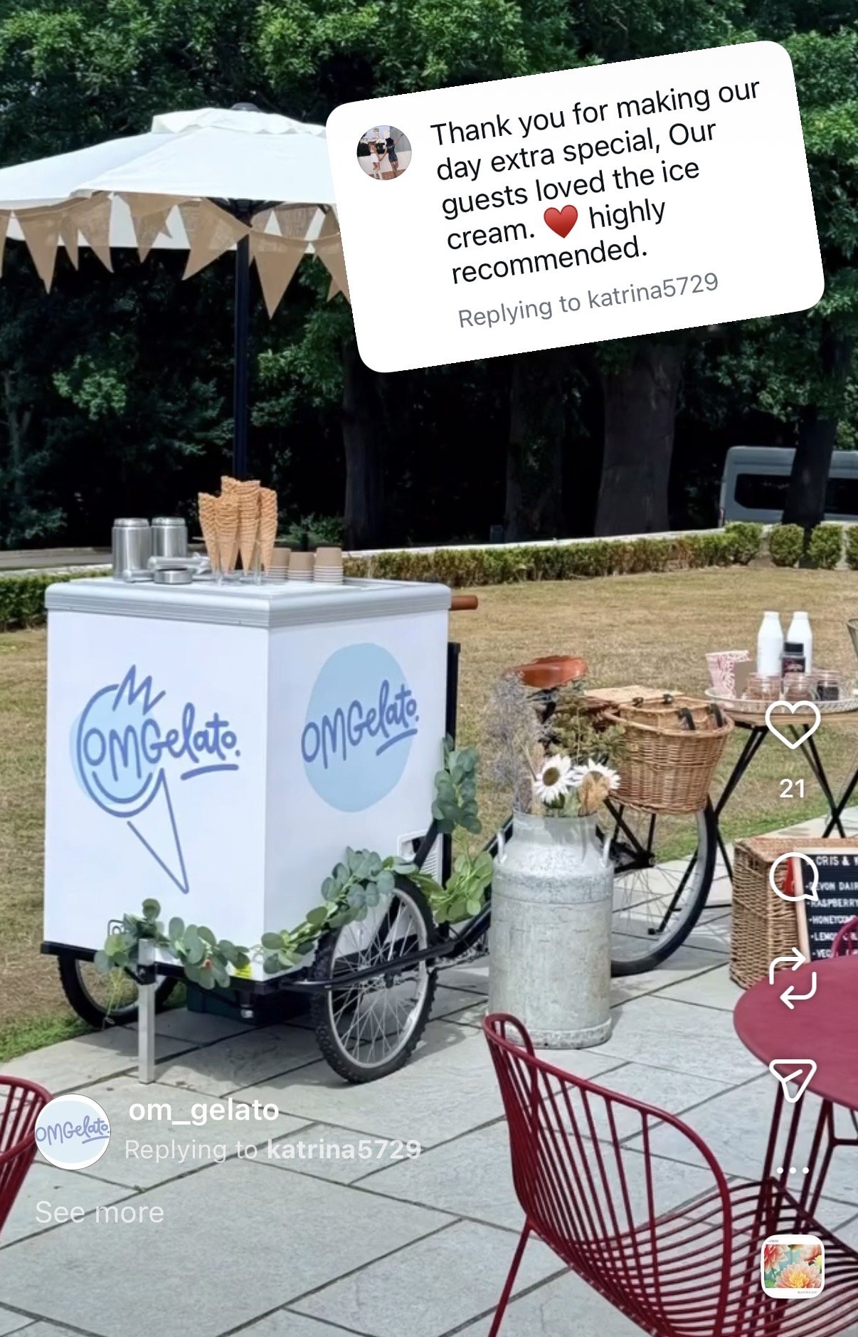 Ice cream cart labeled OMG Gelato, set outdoors on a patio with red chairs, a table, a large milk jug with flowers, and a green hedge in the background, under a white umbrella with bunting.