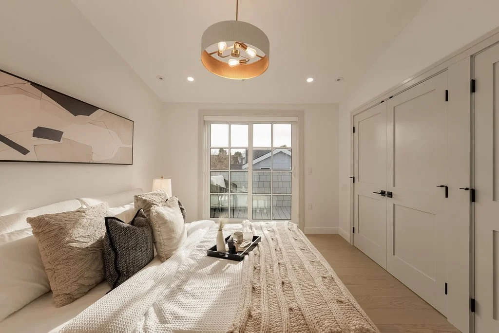 A bright bedroom with a large bed, decorative pillows, a tray with candles, a window, and built-in closet doors.