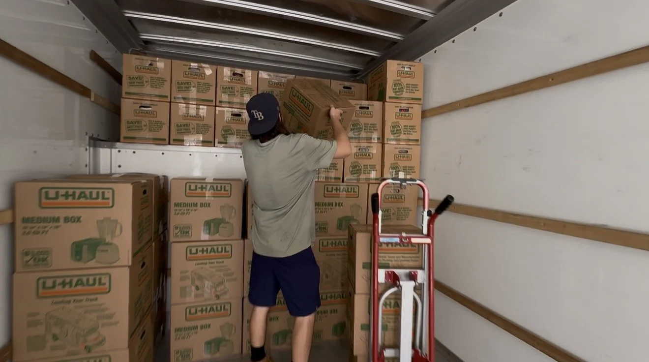 Person stacking U-Haul moving boxes inside a truck.