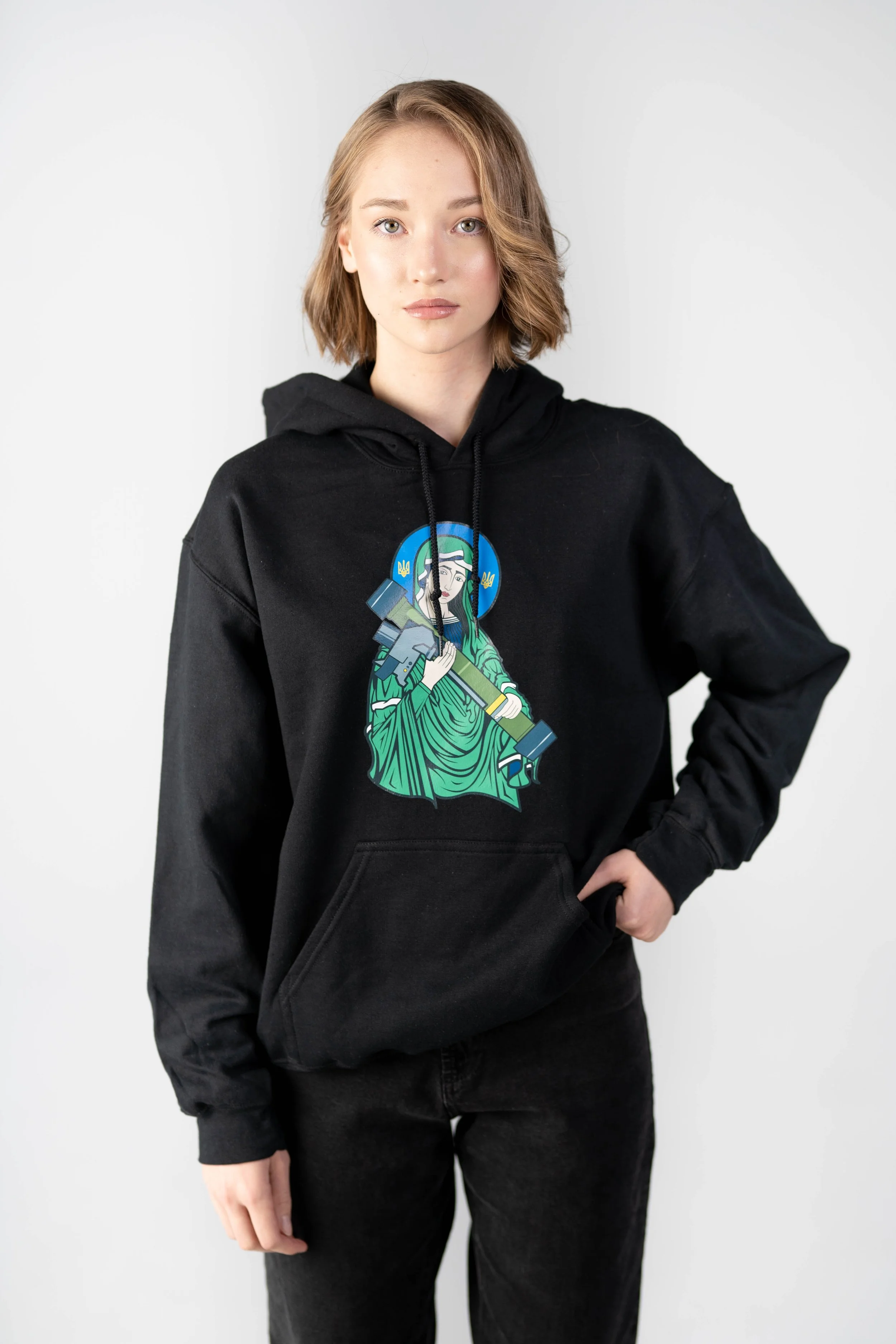 Young woman with shoulder-length blonde hair wearing a black hoodie with a graphic of a woman in green robes holding a large axe.
