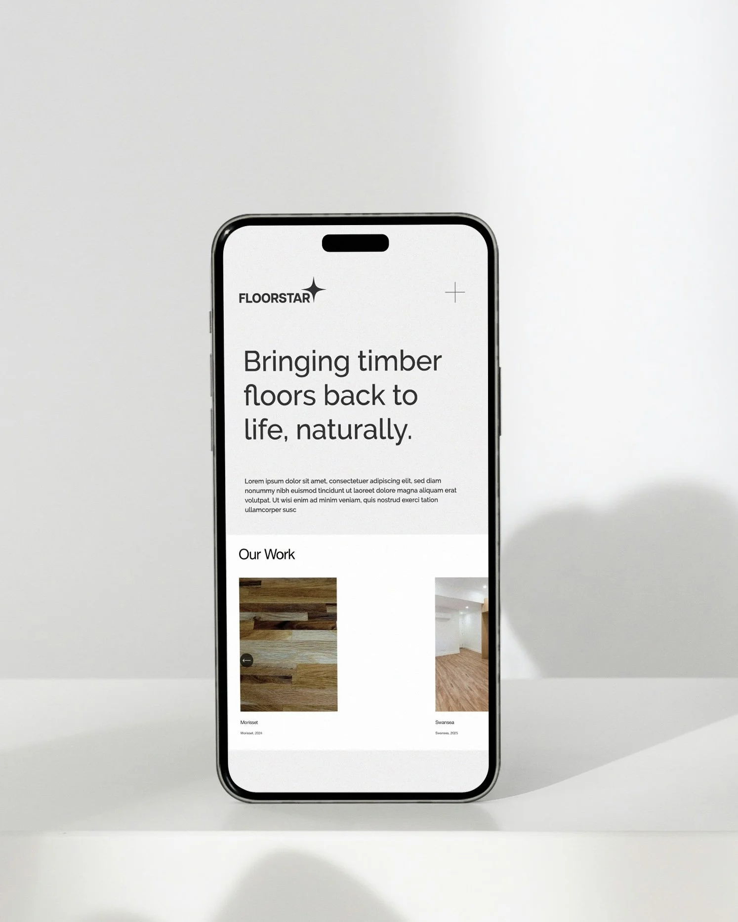 Smartphone displaying a webpage for FLOORSTAR, promoting natural timber floors with images of wooden flooring and an empty room.