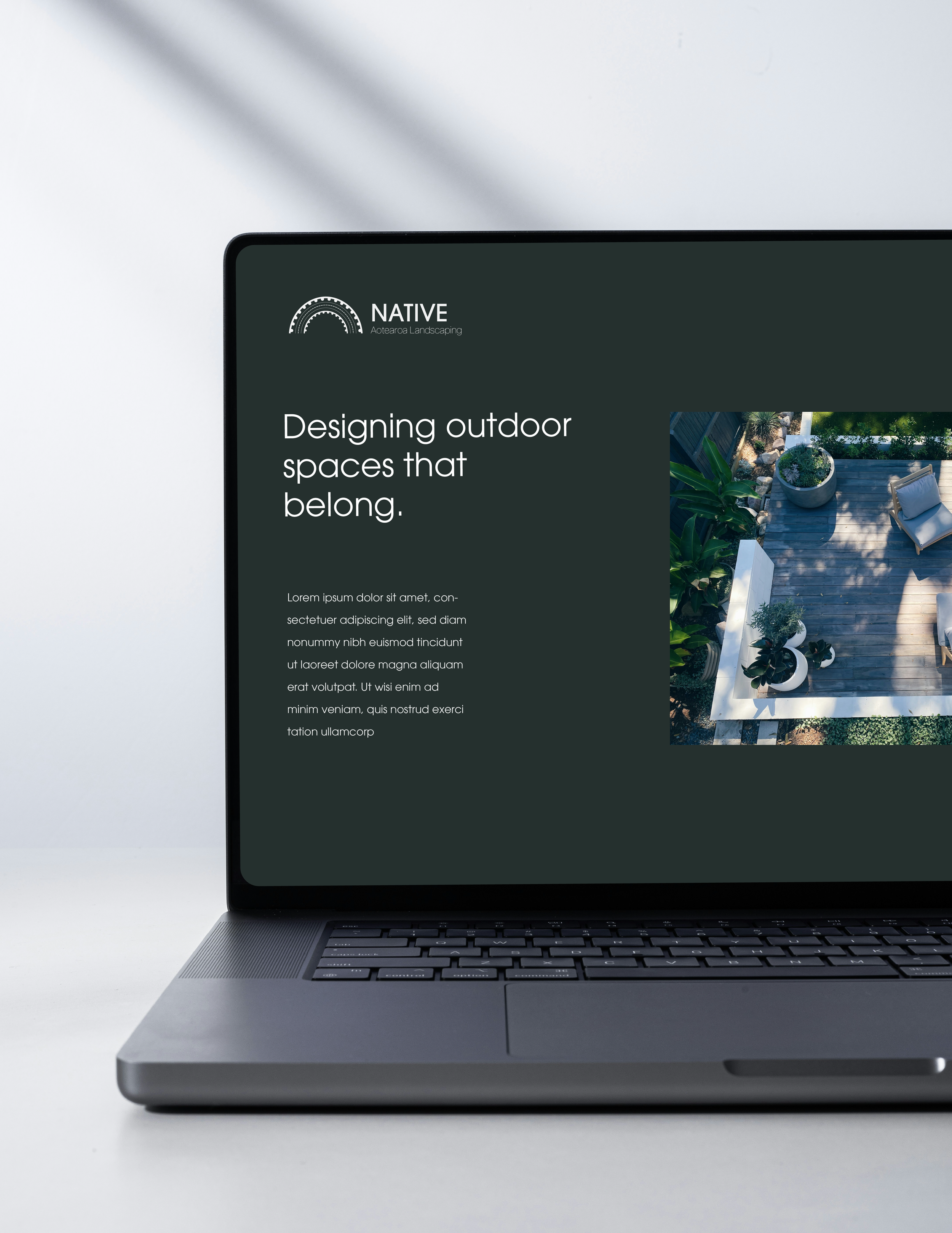 Laptop displaying a website for Native Landscaping, featuring outdoor space design with a photo of a landscaped patio with plants and seating.