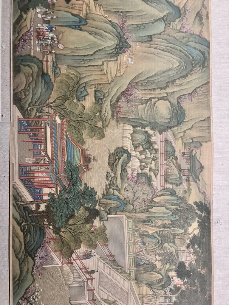 A traditional Chinese landscape painting depicting mountains, waterfalls, trees, and pavilions with people walking across bridges in a serene setting.