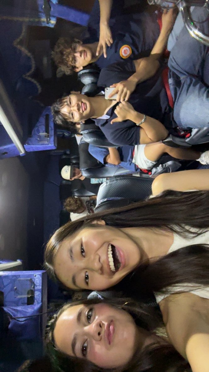 People sitting and smiling on a bus, taking a group selfie