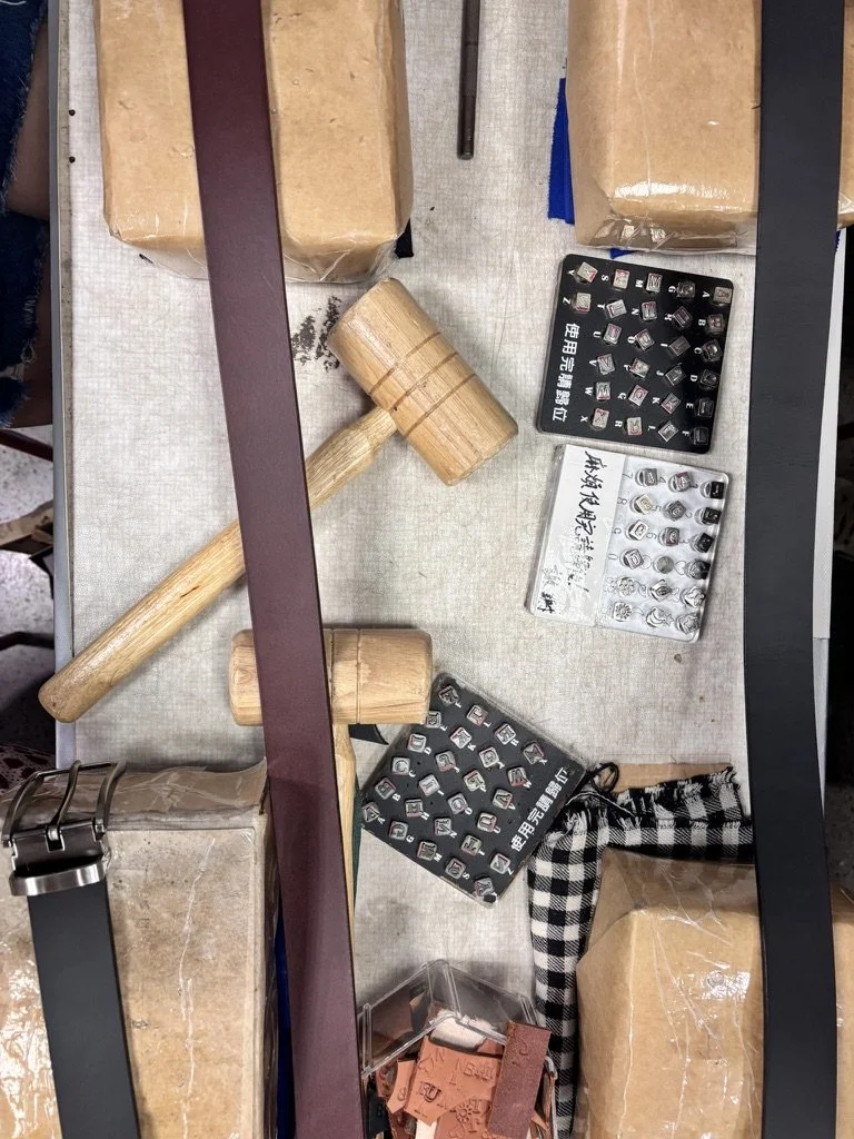 A desk with wooden mallets, cardboard boxes, and several small black and white electronic components organized in trays with Chinese characters, along with some buttons and a plaid cloth.