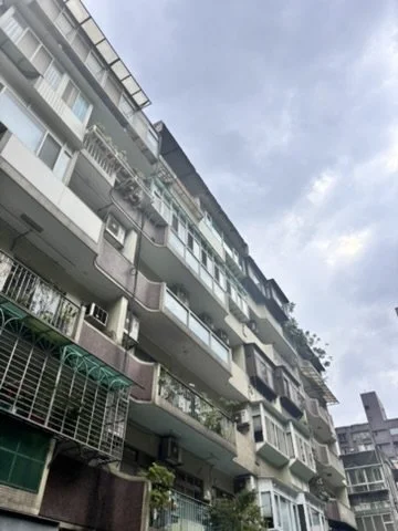 Multiple residential apartments with balconies under a cloudy sky.