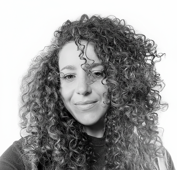 Portrait of a woman (Graphic designer Gabriela) with curly hair, smiling subtly, against a white background.