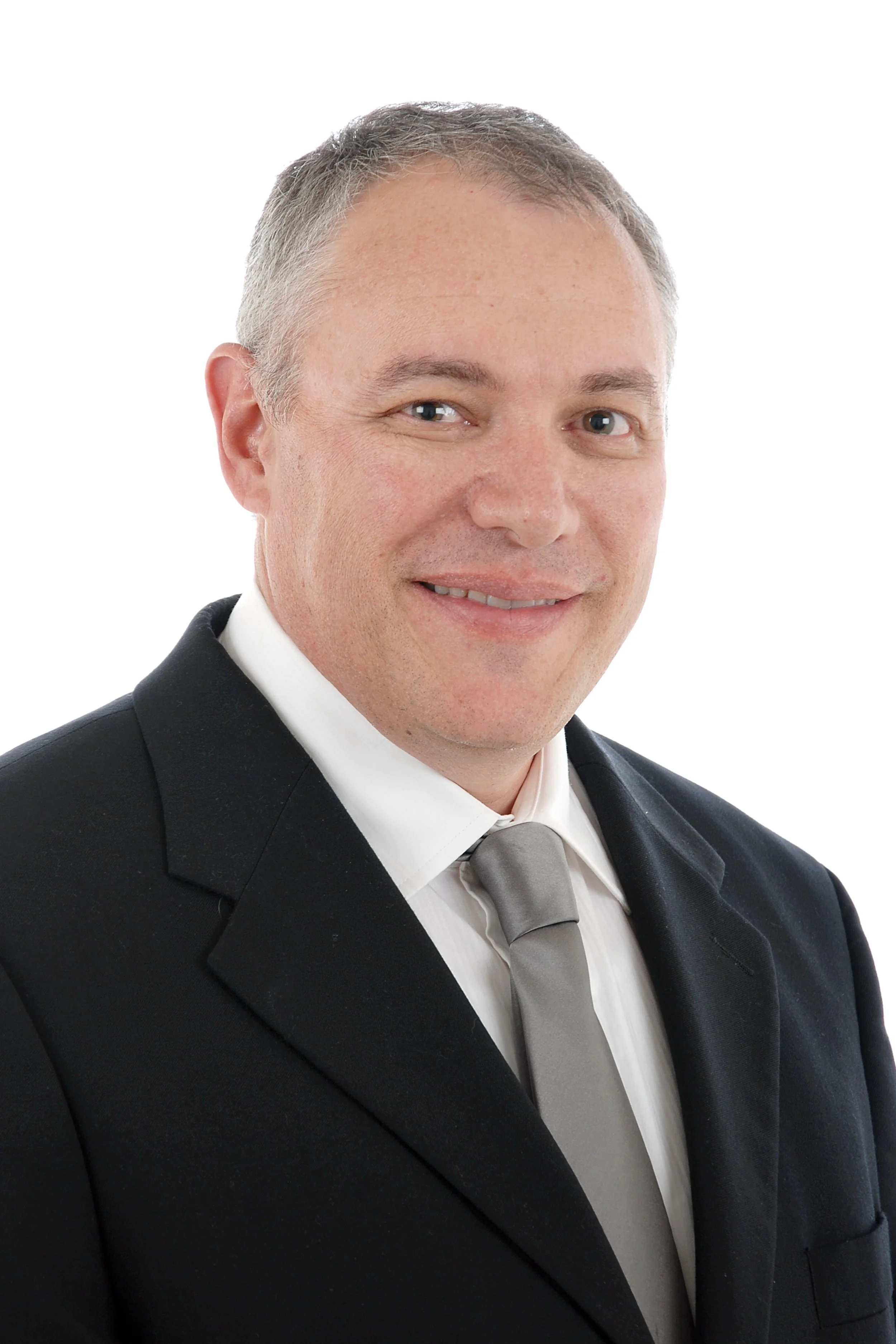 Headshot of a man in a black suit, white shirt, and gray tie, smiling against a white background.