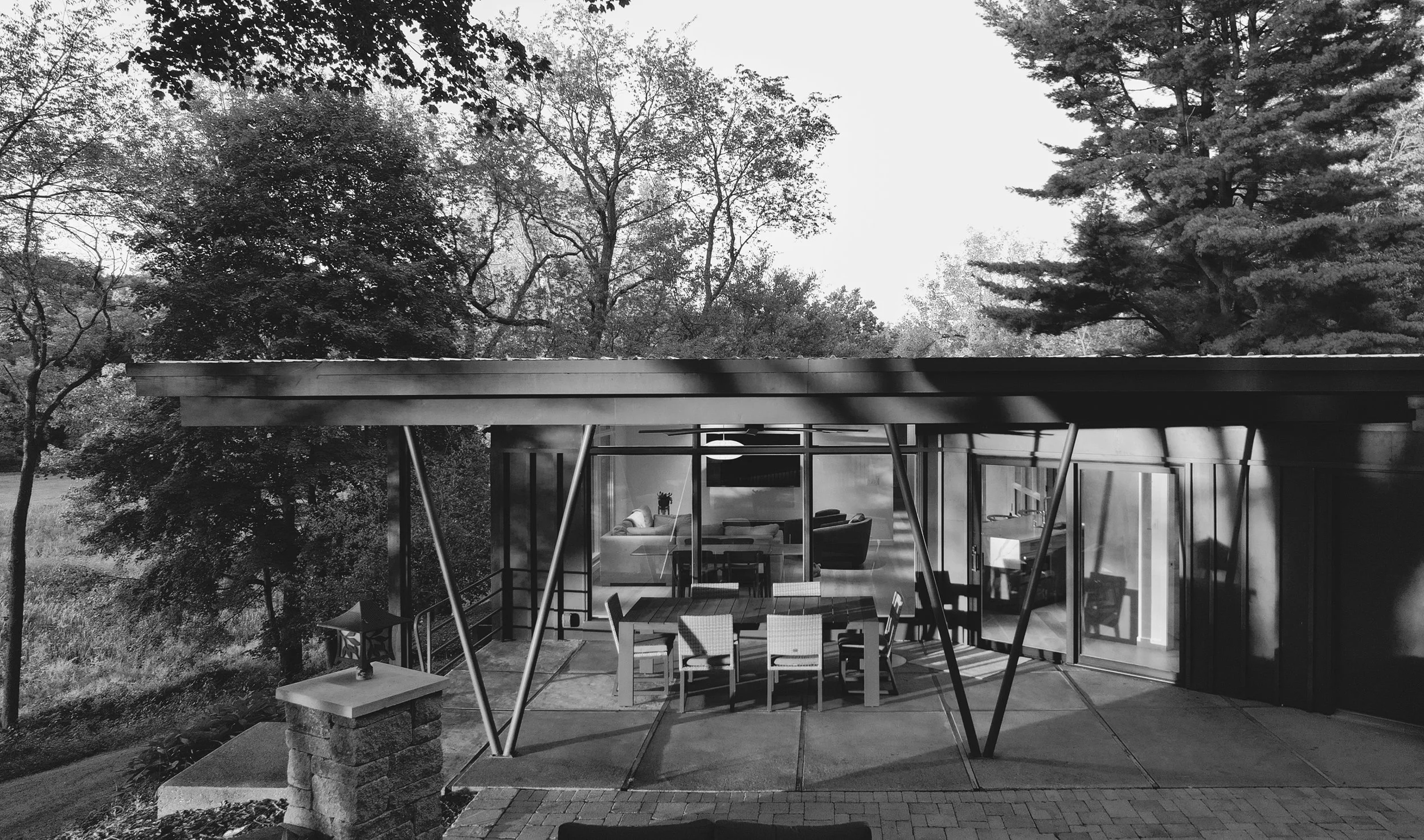 Black-and-white photo showing an aerial view of a midcentury home's outdoor patio, covered by a flat roof.