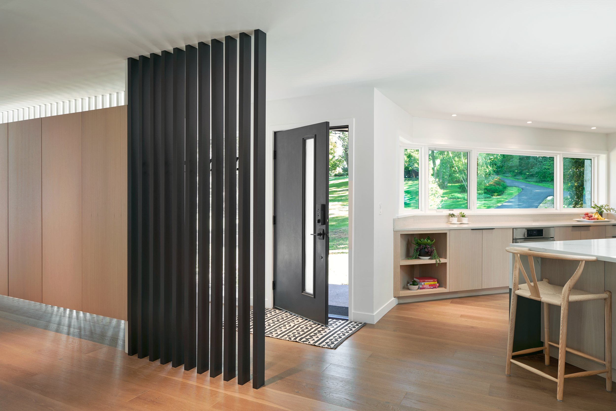 Entryway to midcentury home featuring peek-a-boo slats, hardwood floors and built-in cabinetry