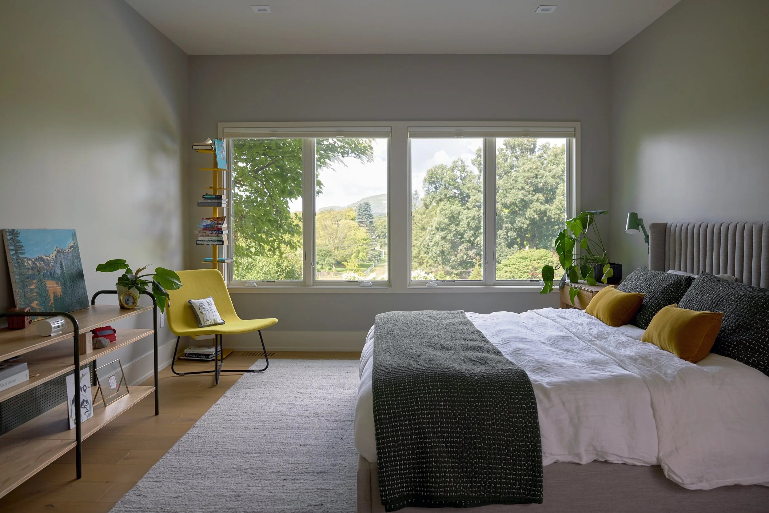 Guest bedroom with large window overlooking a wooded vista