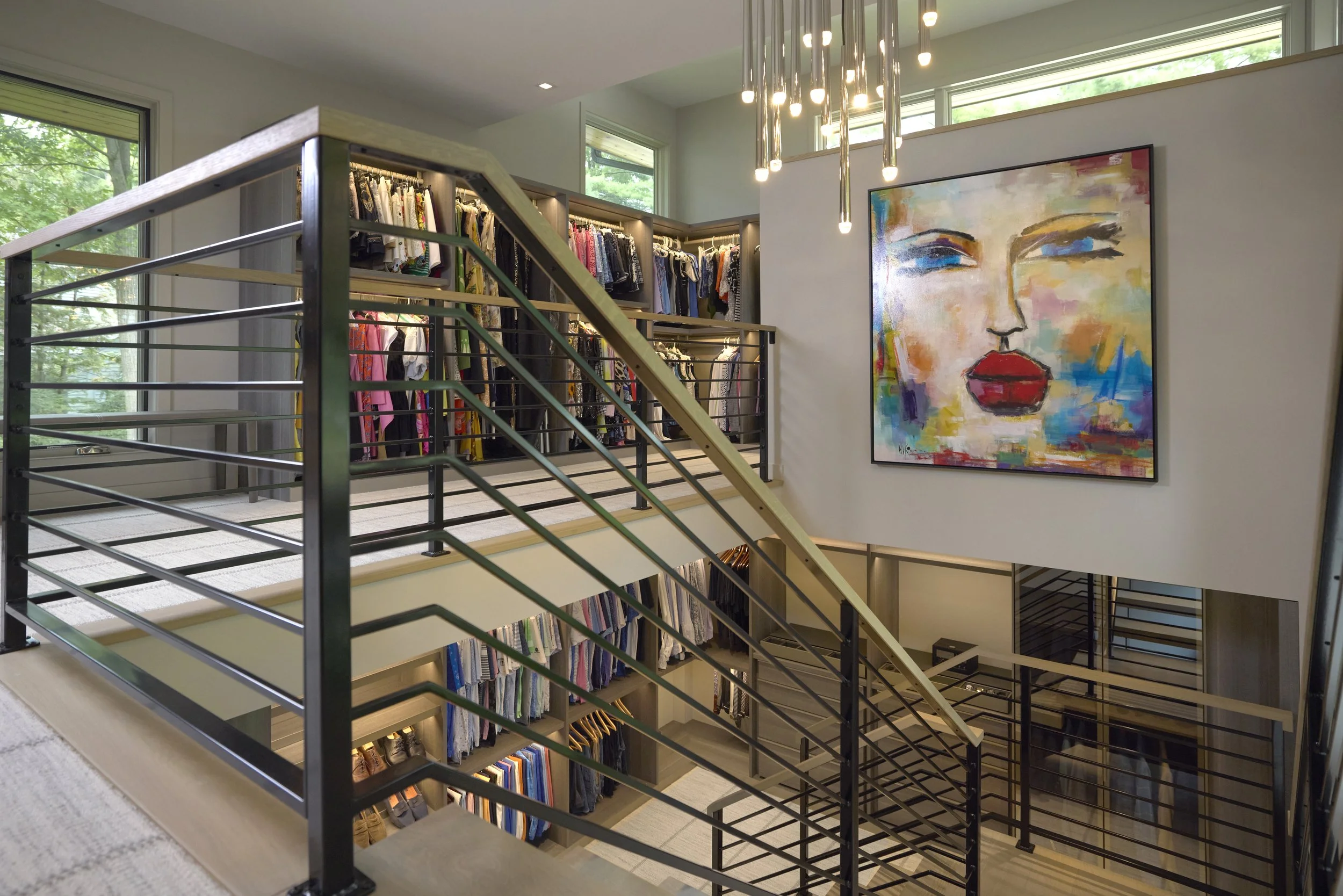 High end, lakefront custom home addition featuring two story contemporary wardrobe master closet with metal hand railings in Ada, Michigan