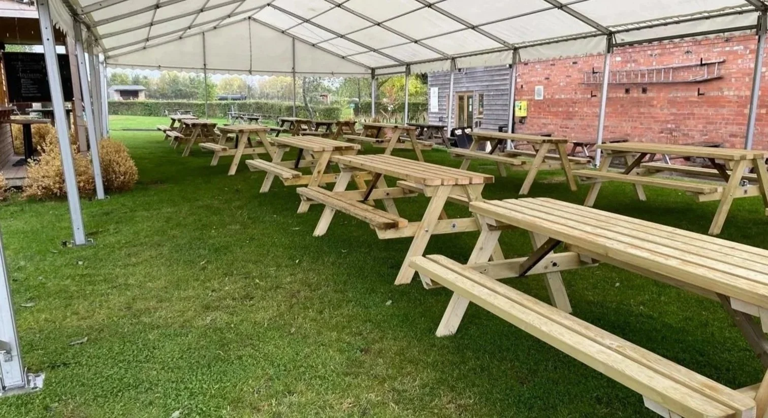 Picinic benches under a stretch tent for a wedding in Cornwall.
