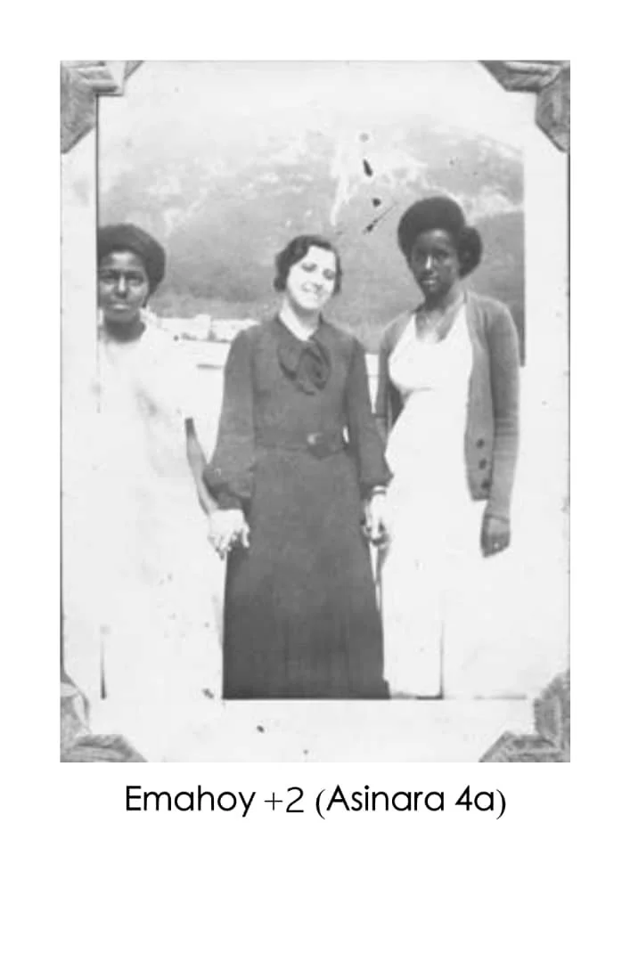 Black and white photo of three women standing outdoors, smiling at the camera, with a landscape background. Text below the photo reads "Emahey +2 (Asinara 4a)."