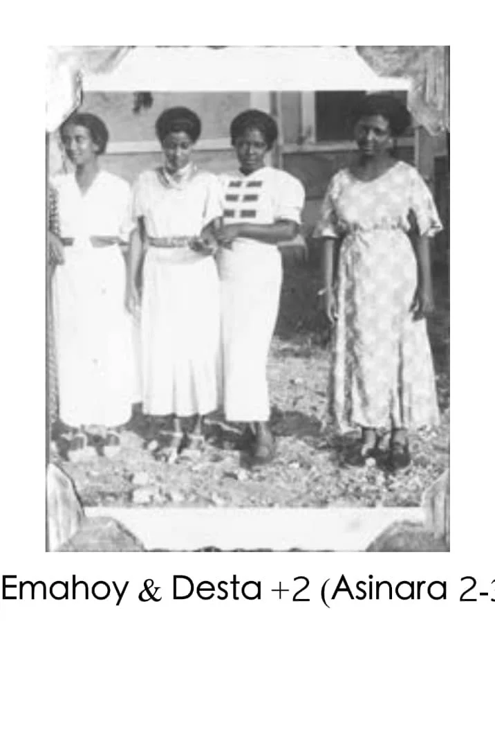 Black and white photograph of four women standing outdoors, with a house in the background. The women are dressed in vintage clothing. The caption reads "Emahoy & Desta +2 (Asinara 2-3)."