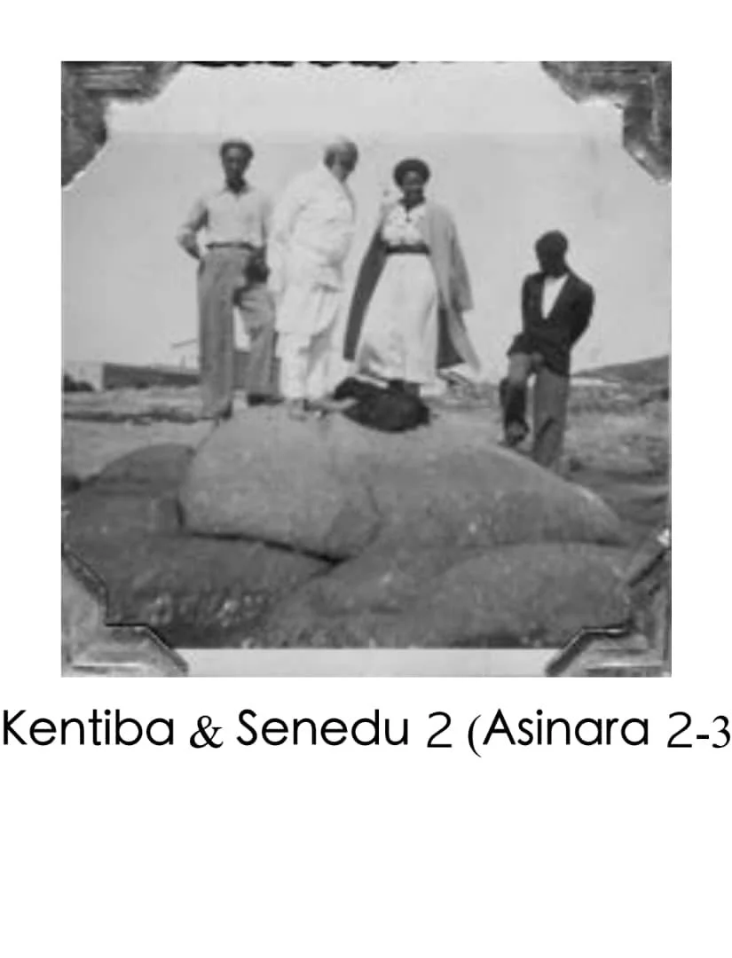 Group of five people standing on rocks outdoors, with a large stone in the foreground, under a partially constructed or damaged structure.