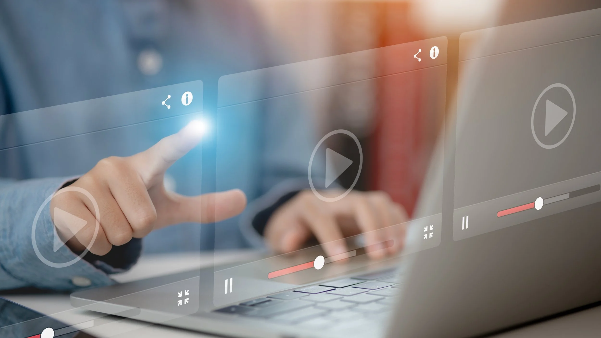 Close-up of a person using a laptop with a virtual user interface overlay showing play, pause, volume, and info icons, with their finger pointing at a highlighted icon.