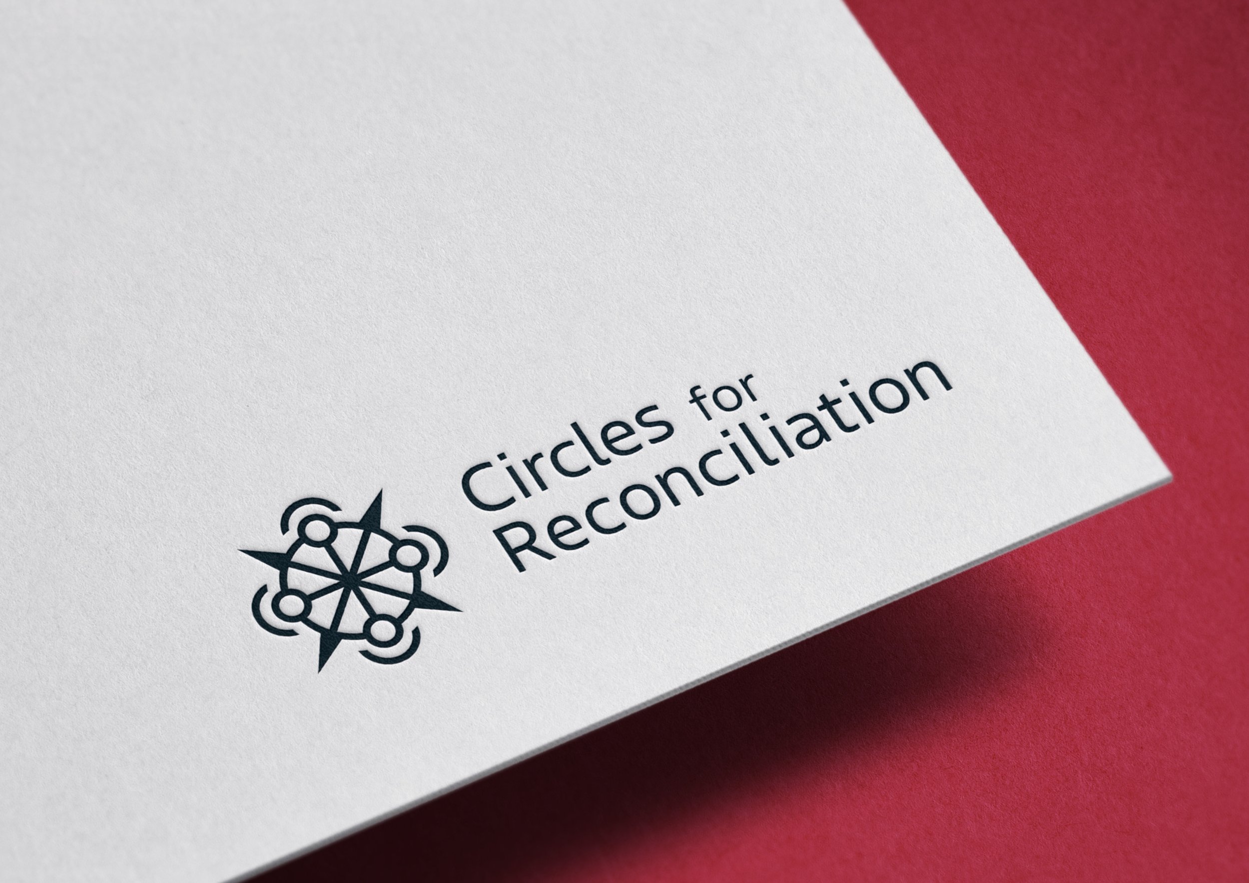 Close-up of a white paper with a logo and text reading 'Circles for Reconciliation' on a red background.