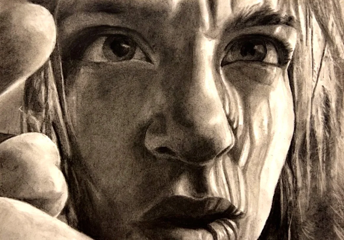 Close-up of a textured sculpture of a woman's face, showing detailed features, with her hand touching her face.