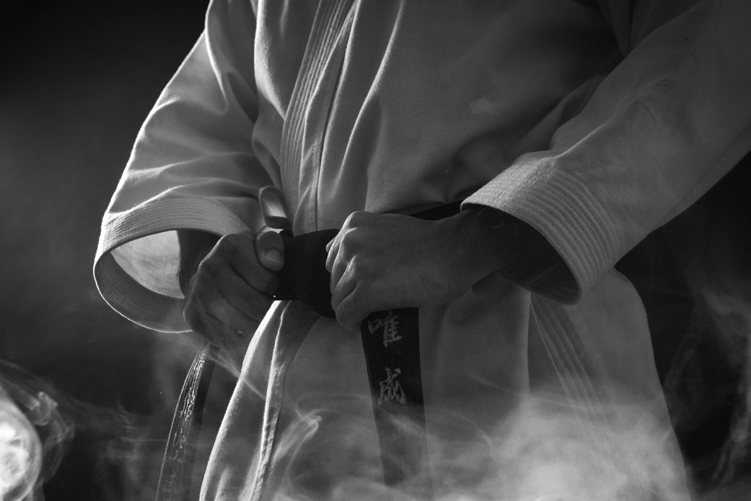 karate uniform and black belt being tied at a martial arts school.