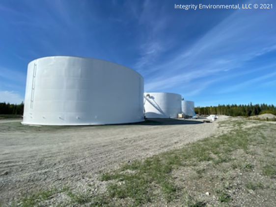 Multiple aboveground bulk fuel storage tanks on a gravel pad at a tank farm facility managed by Integrity Environmental