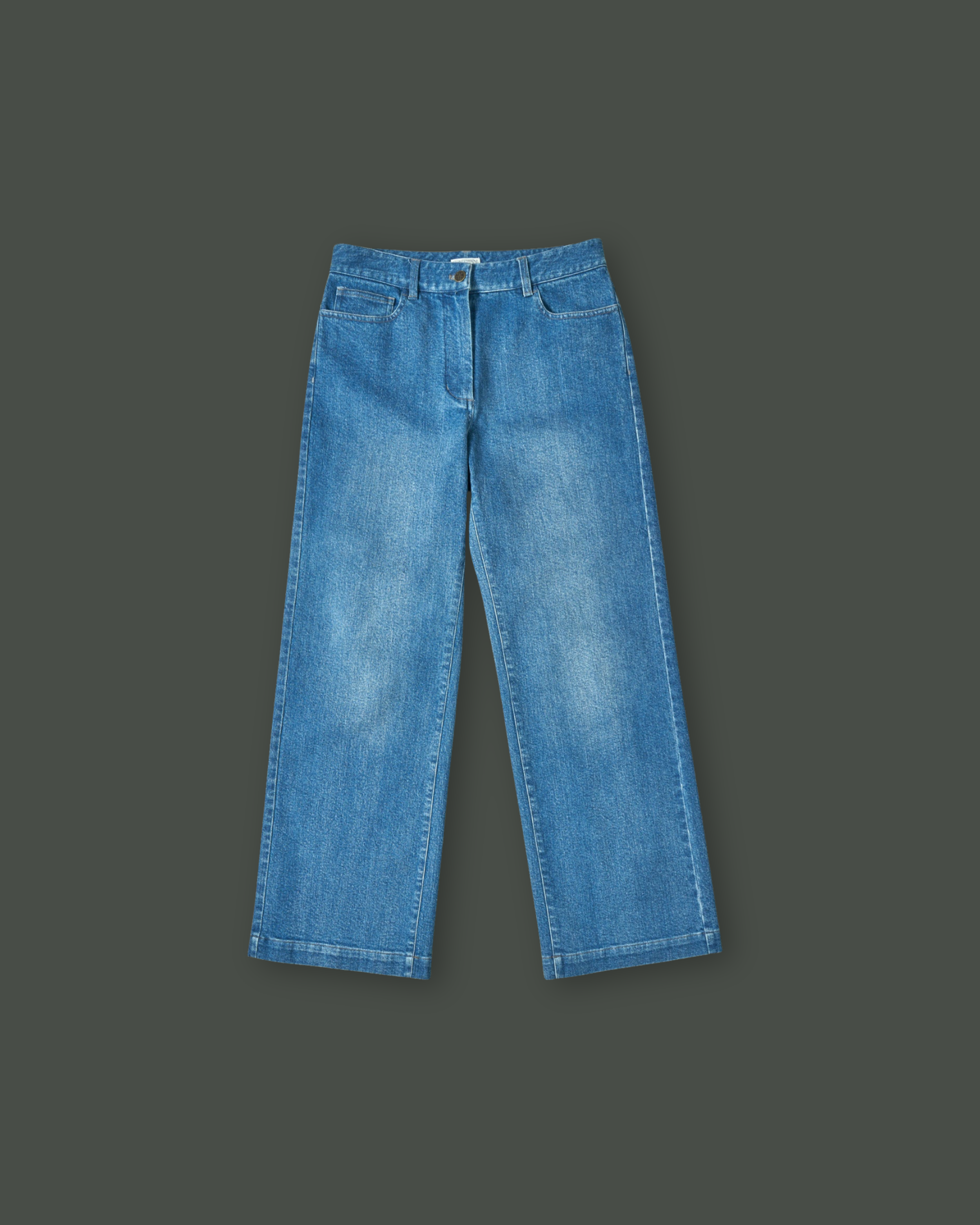 A pair of blue jeans laid flat on a dark green background.