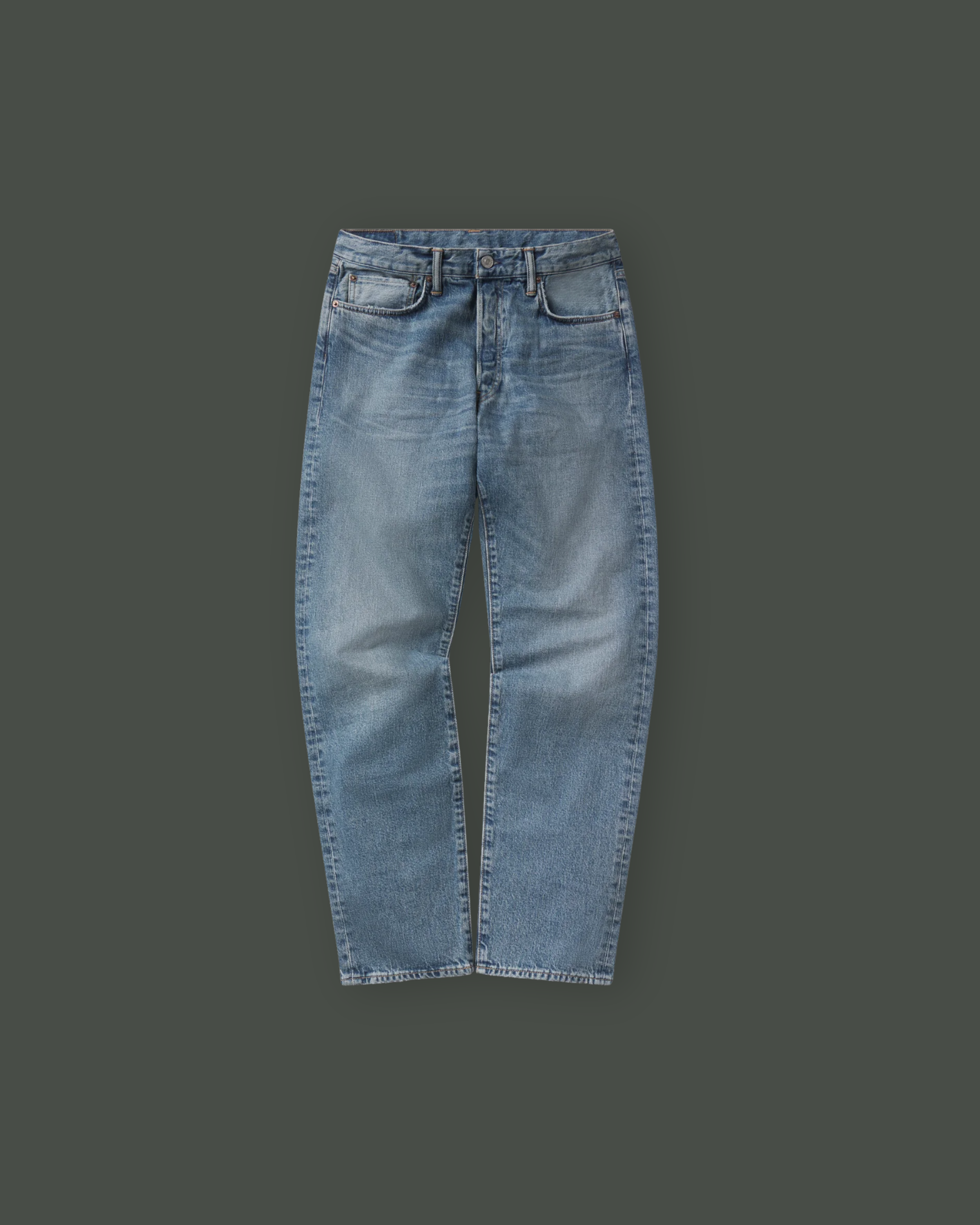Pair of blue jeans laid flat on a dark background.