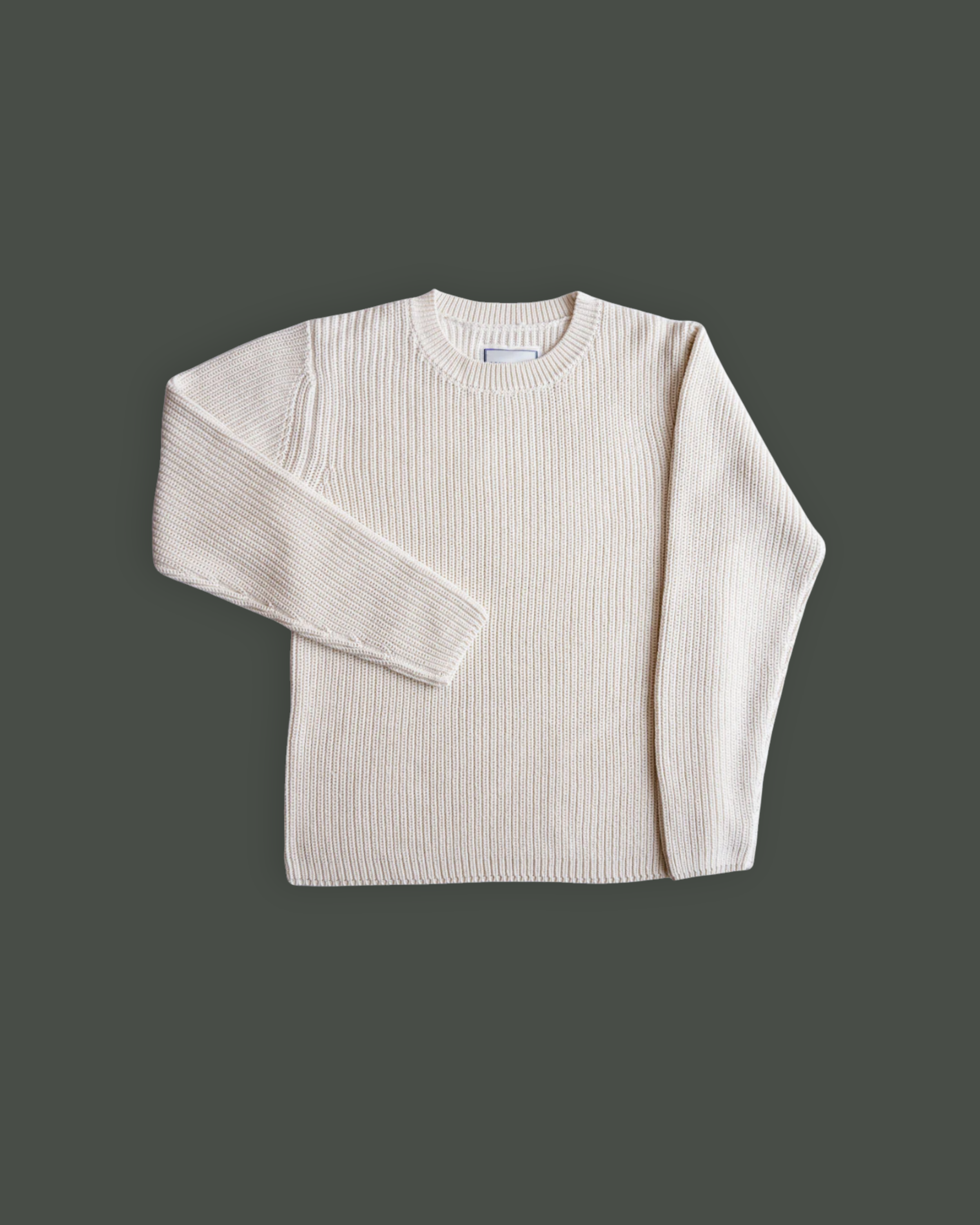 Cream-colored knitted sweater laid flat on a dark grey background.