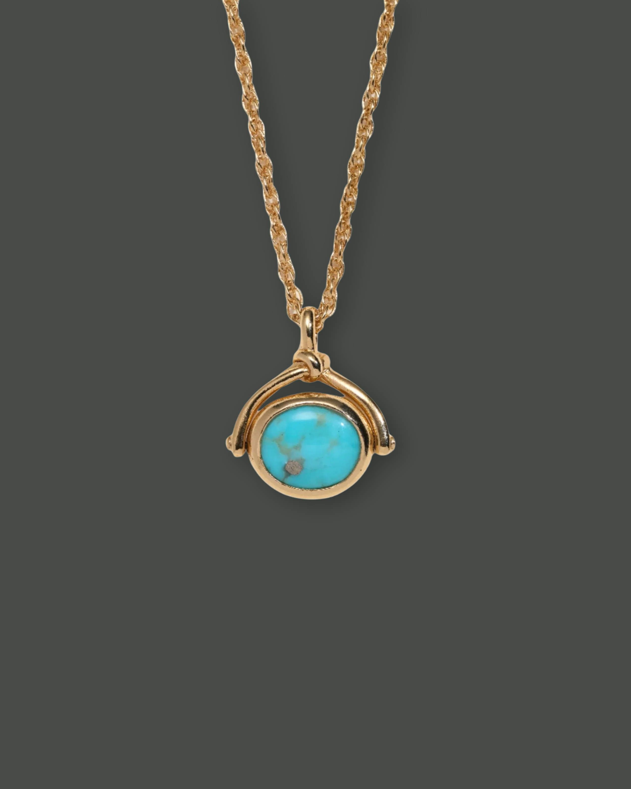 Gold necklace with a circular turquoise pendant on a gray background.