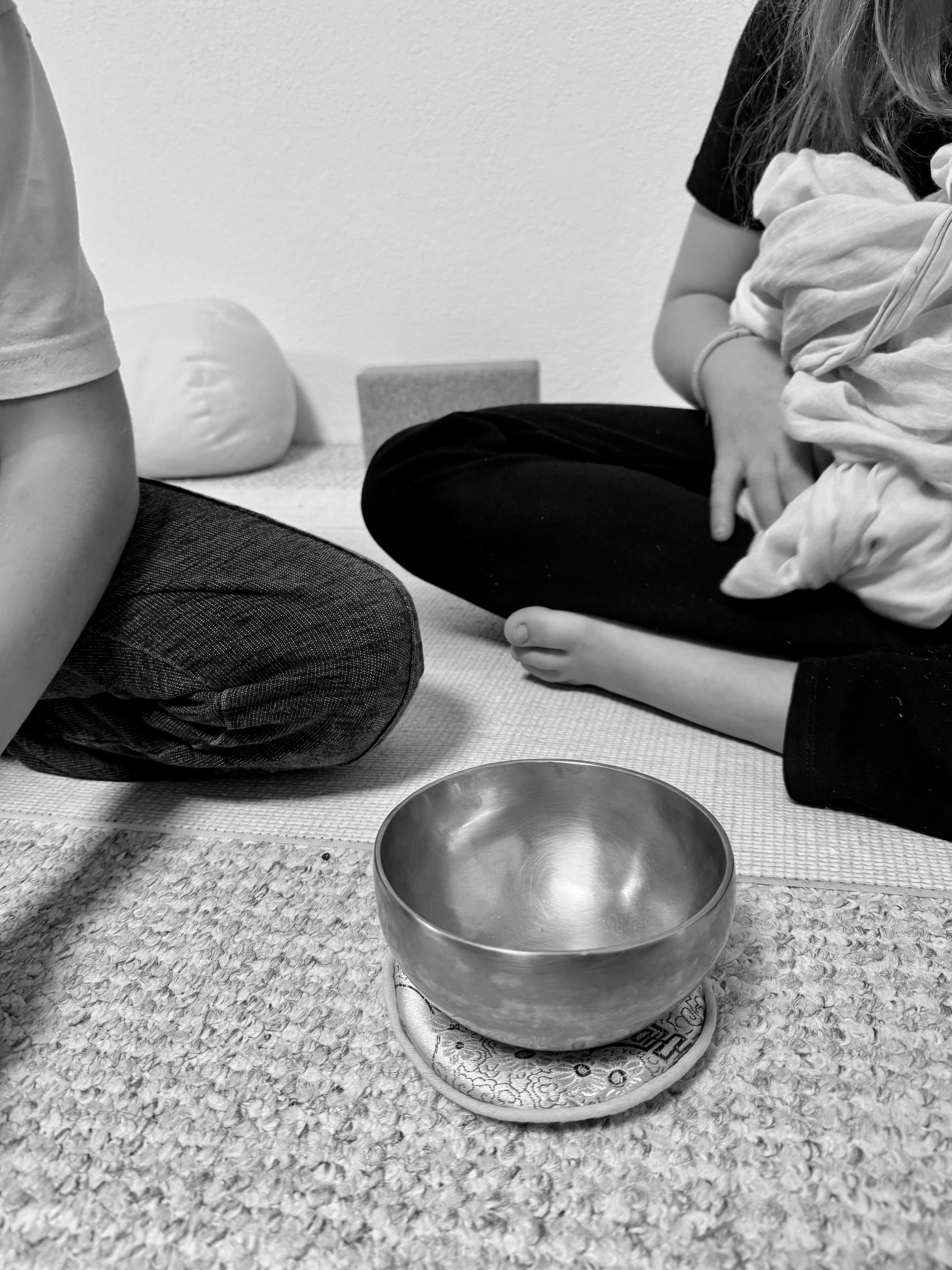 Kinder beim Kinderyoga in Weil am Rhein vor einer Klangschale im Schneidersitz