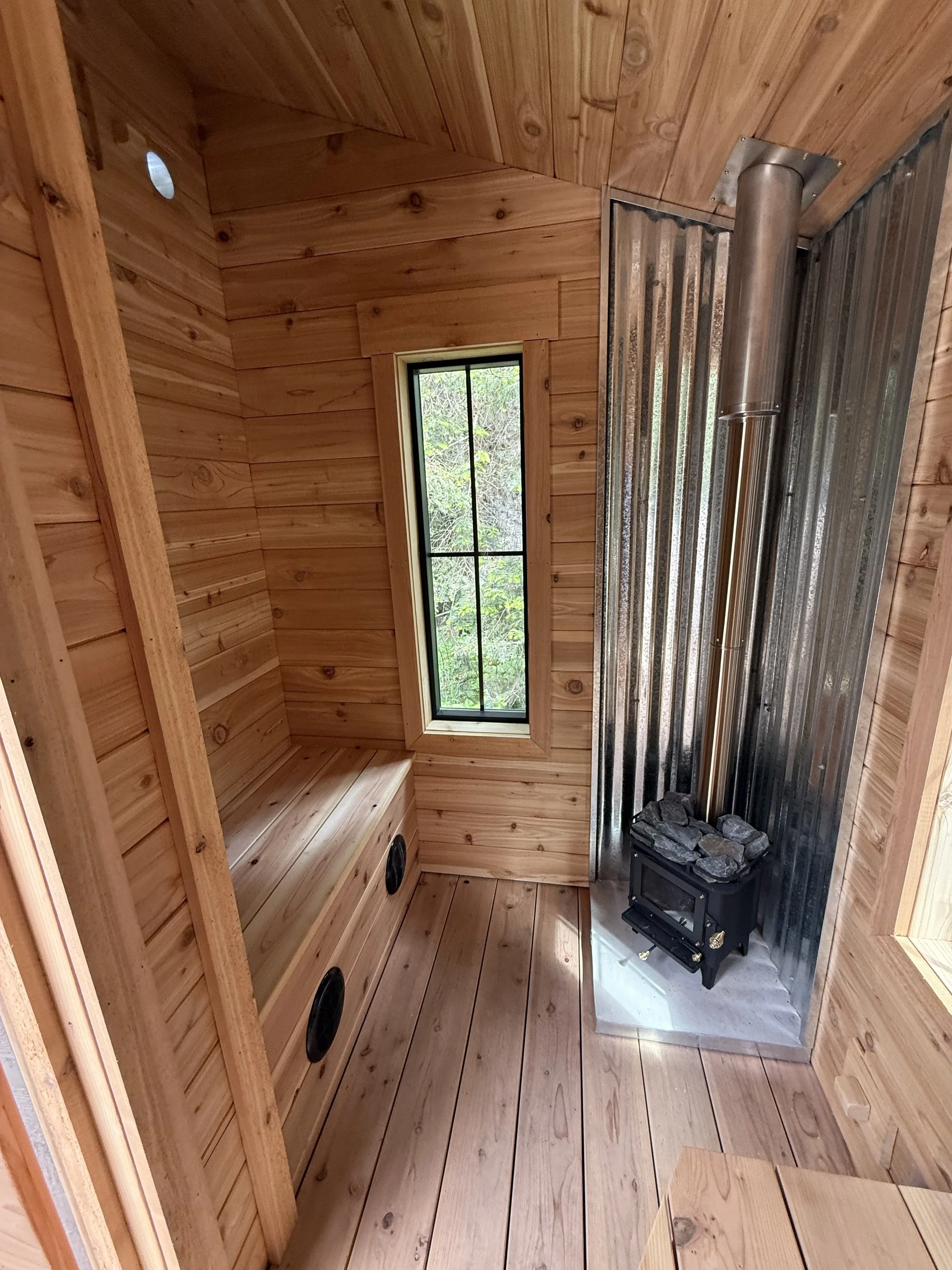 Custom Sauna with cold plunge, built by CUB Saunas, cedar interior wood paneling, with small wood-fired stove, in Stevensville, Montana