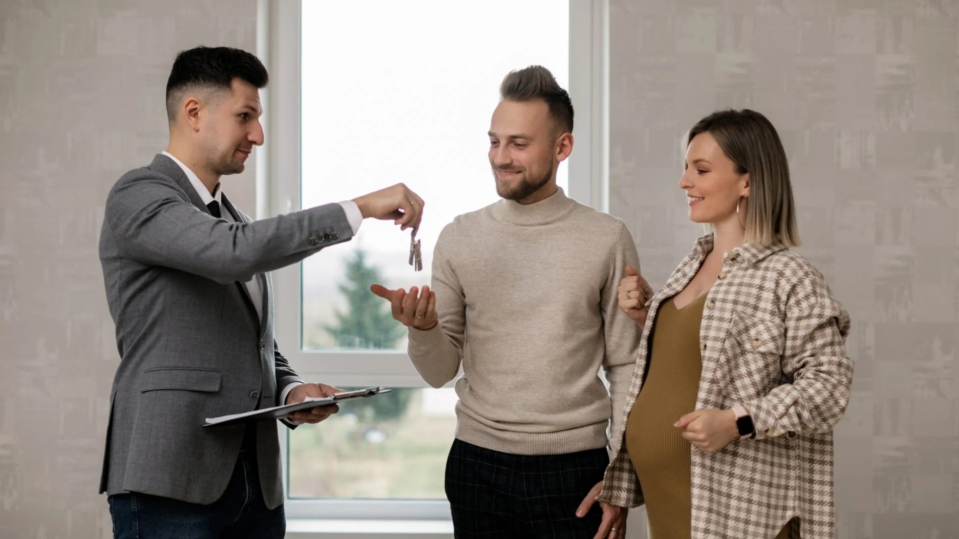 Free Home Value Now - A real estate agent is handing over house keys to a couple during a home buying process.