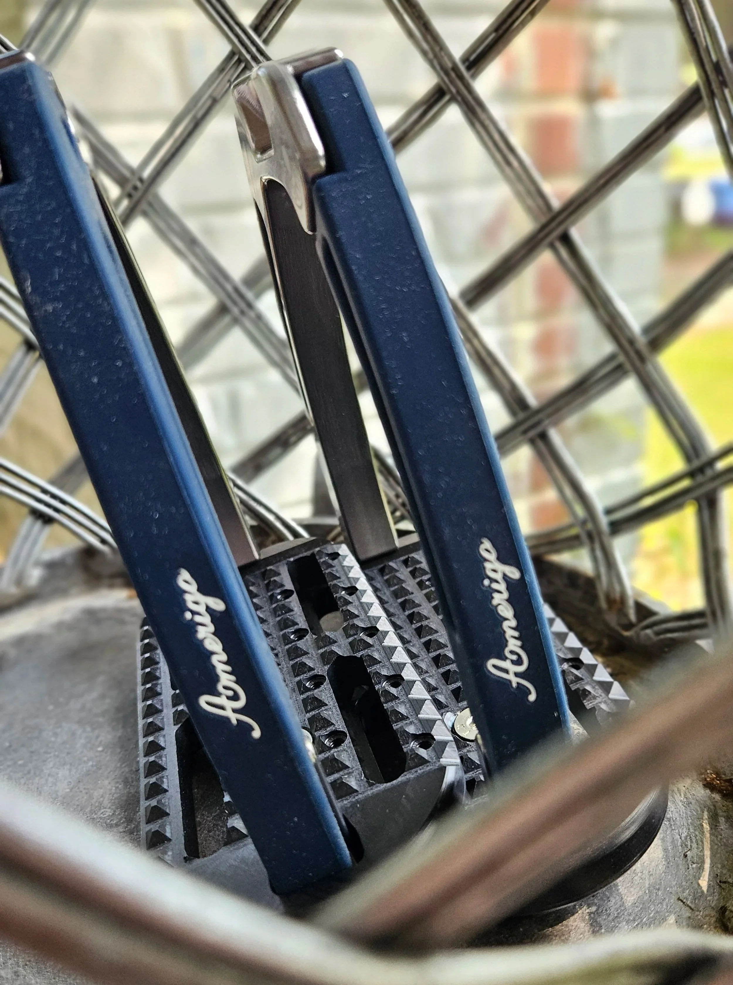 Close-up of navy Amerigo safety stirrups with black tread, photographed in a wire basket outdoors