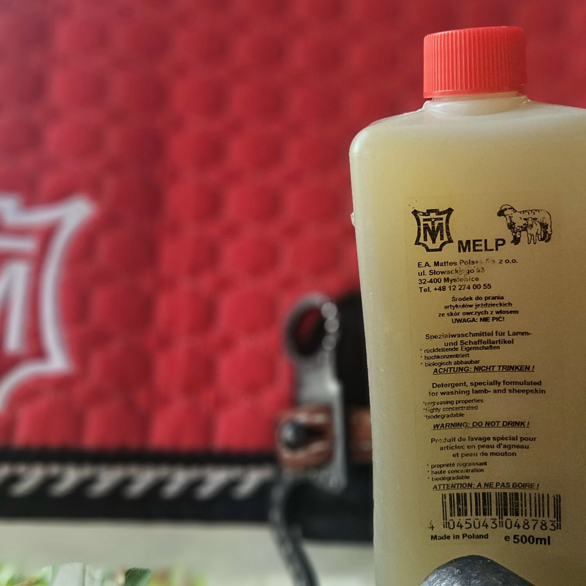 500ml bottle of Mattes MELP sheepskin detergent with red cap, placed in front of a red quilted saddle pad.