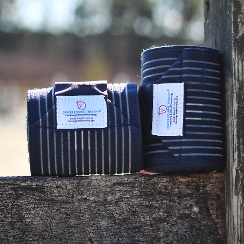 Draper Therapies Perfect Polo Wraps in green with silicone stripes, displayed outdoors on a wooden fence with yellow wildflowers