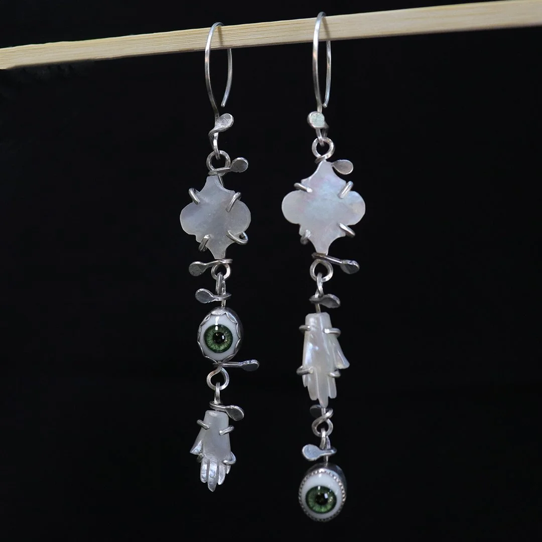 Handmade silver earrings featuring carved mother-of-pearl drops