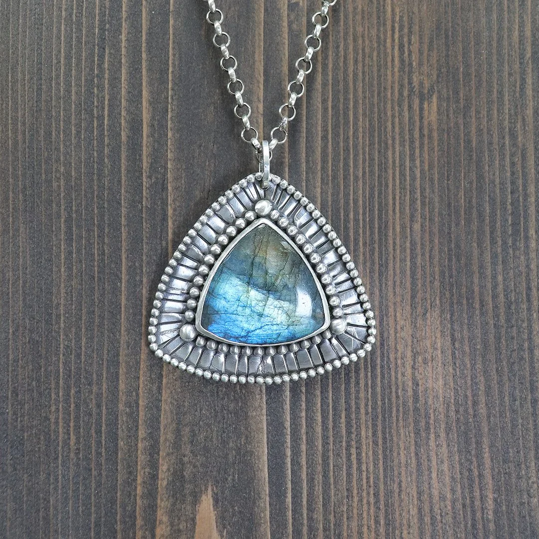 Sterling silver labradorite pendant with blue flash on wood background