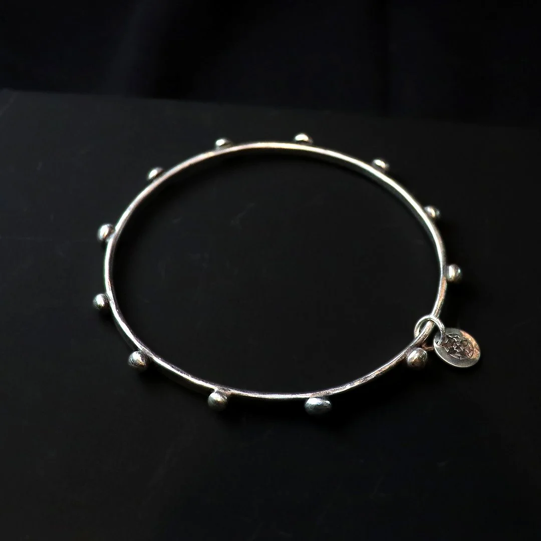 Handcrafted silver bangle featuring repeating beads
